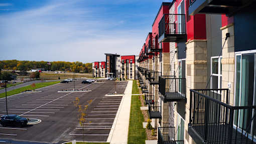 A parking lot in front of a row of apartment buildings.
