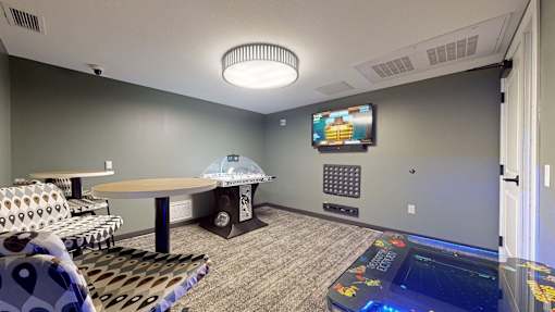 A room with a table, chairs, and a television mounted on the wall.