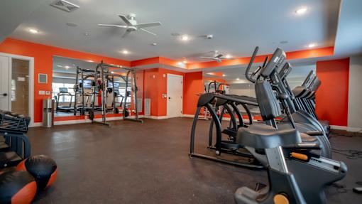 A gym with orange walls and a variety of exercise equipment.