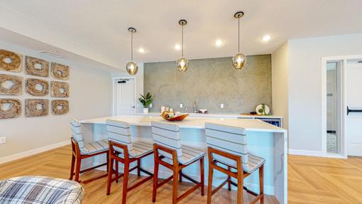 A kitchen with a white counter and wooden chairs.
