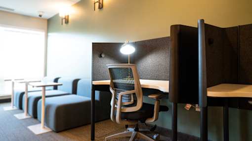 A room with a desk, chairs, and a couch.