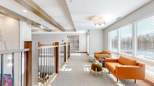 A long hallway with orange chairs and tables on the right side.
