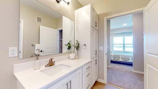A bathroom with a white sink and mirror.
