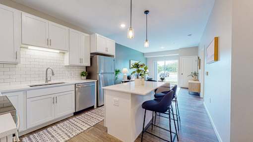 A kitchen with white cabinets and a blue chair.