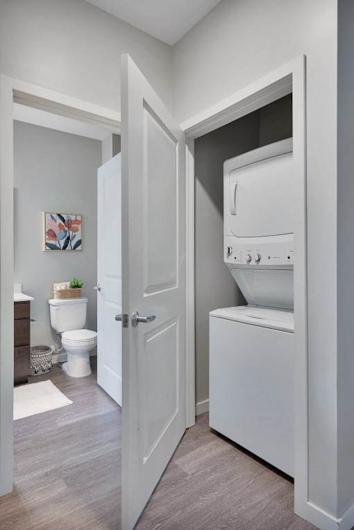 A white door opens to a bathroom with a toilet and a washing machine.