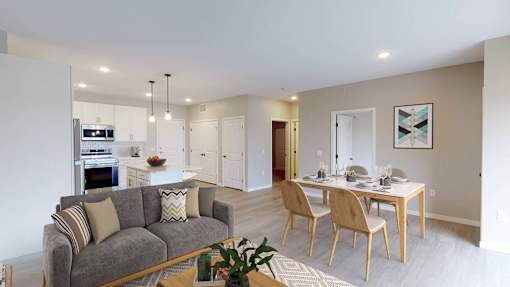 A modern living room with a grey couch and a dining table set for four.