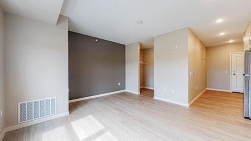 A spacious room with wooden flooring and white walls.