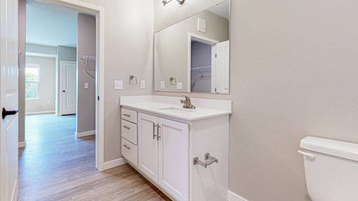 A white bathroom with a sink, mirror, and bathtub.