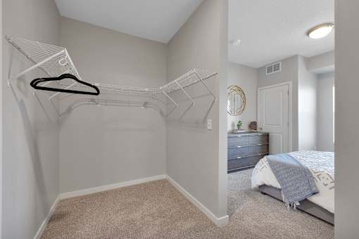 A bedroom with a bed, dresser, and a hanger on the wall.