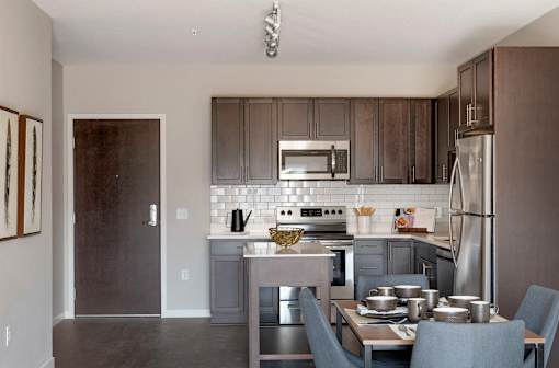 A modern kitchen with a dining table set for two.