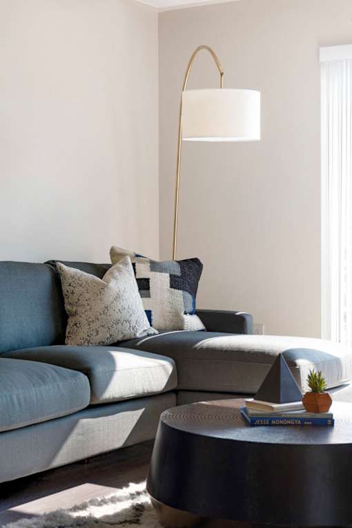 A grey couch with a white lamp above it.