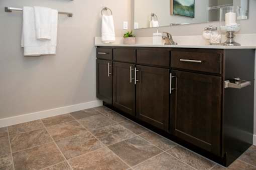 A bathroom with a brown cabinet and a tiled floor.