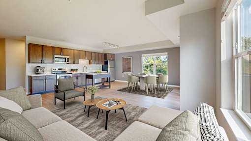 A modern living room with a kitchen in the background.