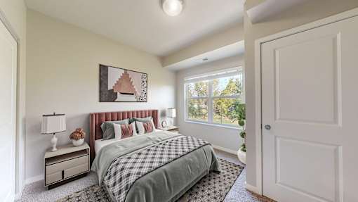 A bedroom with a bed, nightstand, and window.