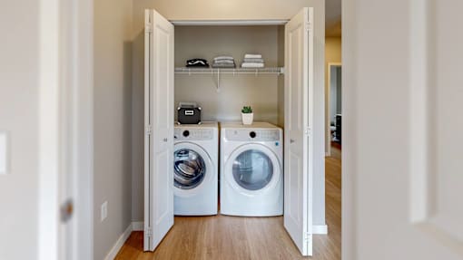 A laundry room with two washing machines and a shelf with towels and a plant.