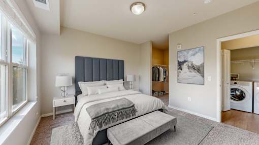 A bedroom with a large bed and a washing machine in the laundry area.