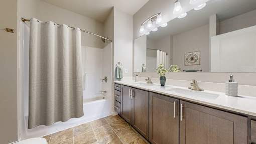A bathroom with a shower curtain, two sinks, and a large mirror.