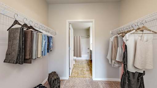 A hallway with clothes hanging on both sides and a bag on the floor.