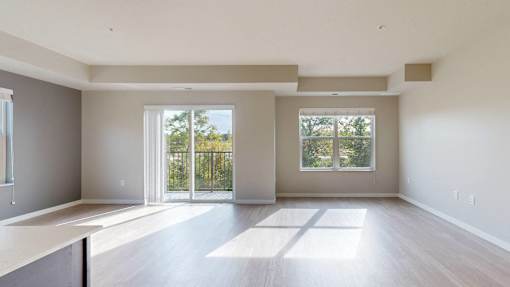 A large, empty room with a sliding glass door leading to a balcony.