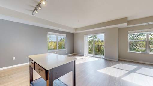 A spacious room with a table and chairs in the foreground and sliding glass doors leading to a balcony.