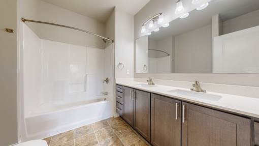 A bathroom with a white tub, sink, and mirror.