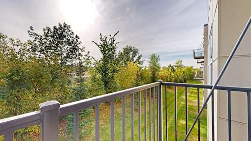 A balcony with a metal railing overlooks a green landscape.