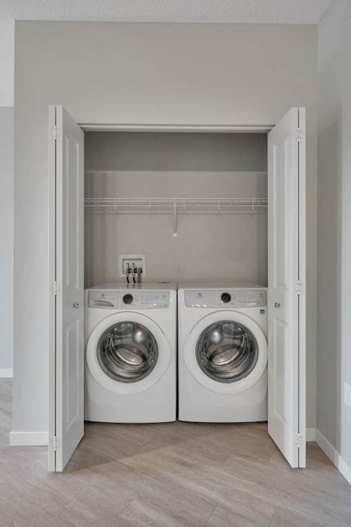 A laundry room with two washing machines and a white door.