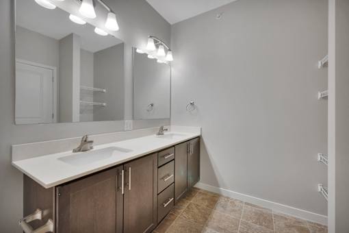 A bathroom with a sink, mirror, and lighting fixtures.