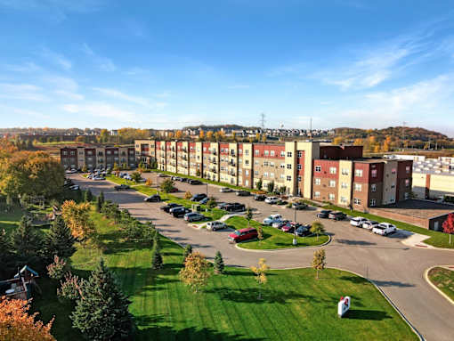 A large apartment complex with a parking lot in front.