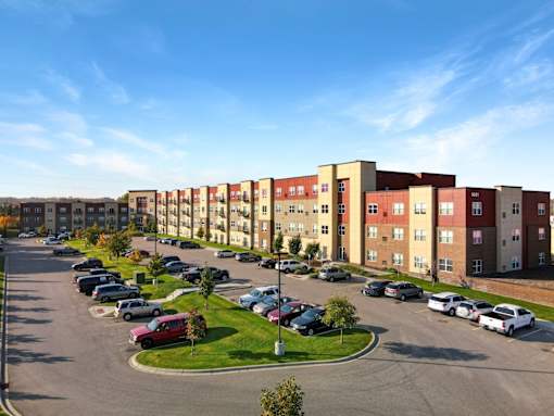A parking lot in front of a row of apartment buildings.