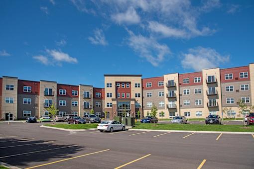 A parking lot in front of a multi-story apartment building.