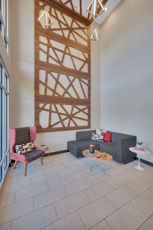 A living room with a grey couch, a red chair and a wooden wall panel.