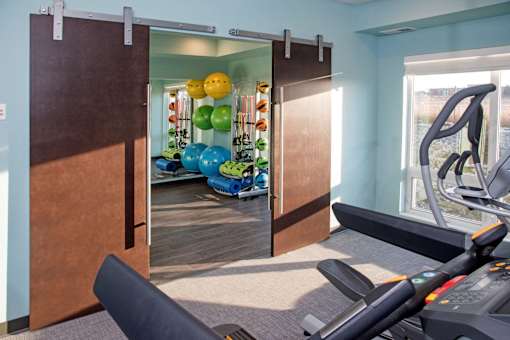 A gym with a treadmill, exercise balls and a mirror.