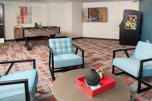 A room with a foosball table and two chairs.