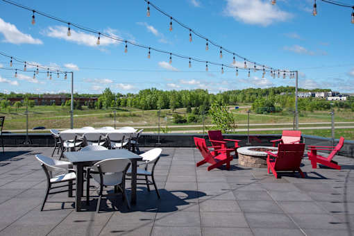 A patio with a table and chairs and string lights.
