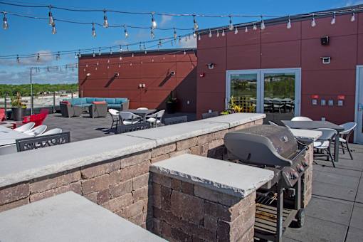 A red building with a grill on the patio.