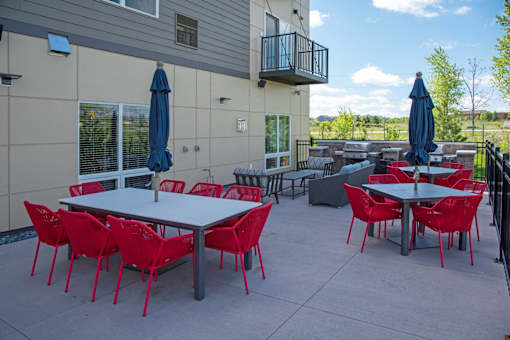 A patio with red chairs and tables.