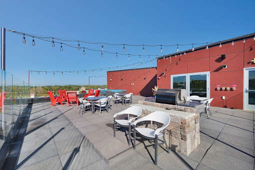 A patio with red chairs and tables is set up on a rooftop.