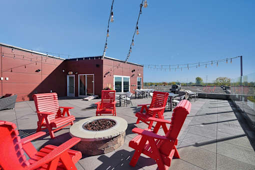 A patio with red chairs and a fire pit.