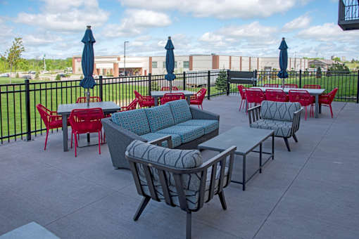 A patio with red chairs and blue umbrellas.