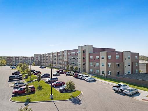 A parking lot in front of a large apartment building.