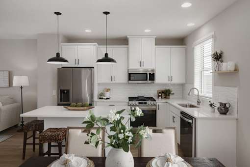A modern kitchen with a dining table set for two.