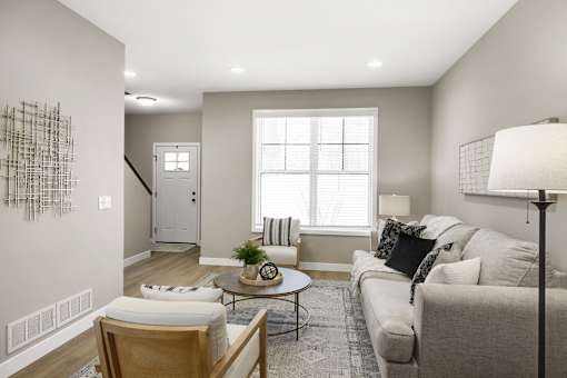A living room with a couch, chair, and a table with a plant on it.