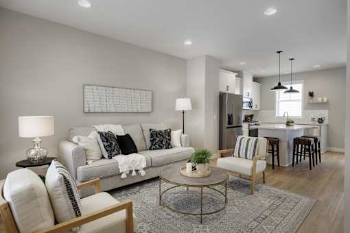 A modern living room with a grey sofa, a coffee table, and a dining area in the background.