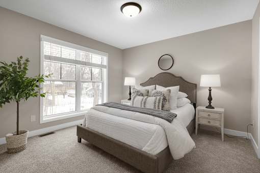 A bedroom with a large bed, a nightstand, and a potted plant.