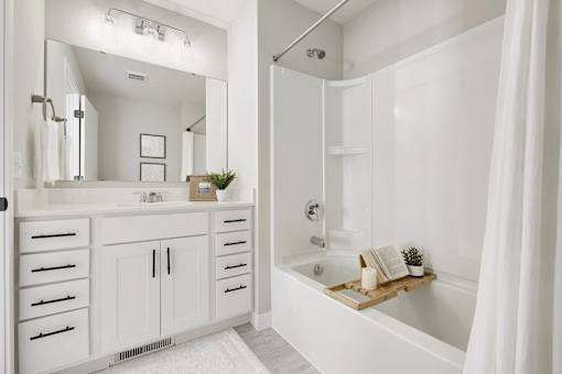 A white bathroom with a large mirror and a bathtub.