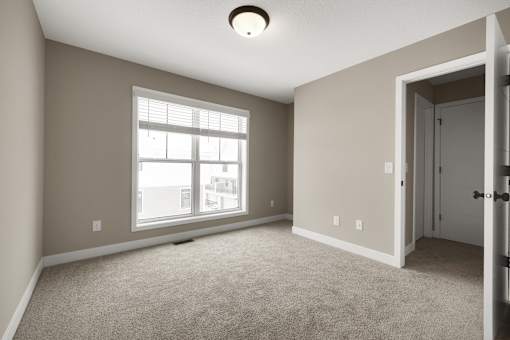 A room with a carpeted floor, a window, and a door.