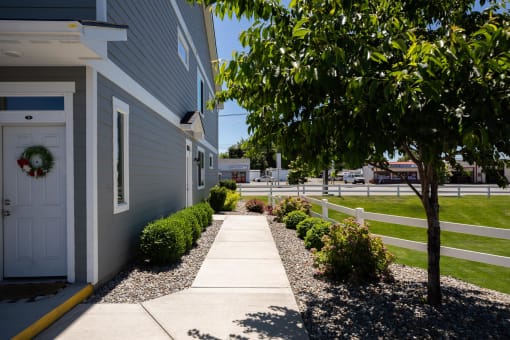 a sidewalk in front of a house with a tree at The Brix Apartments, Spokane Valley