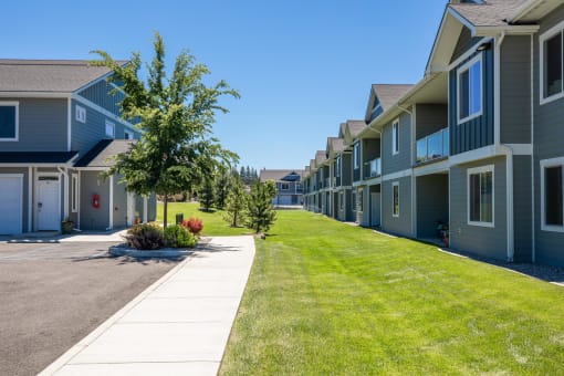 a row of houses with a lawn and a sidewalk at The Brix Apartments, Spokane Valley, WA, 99037