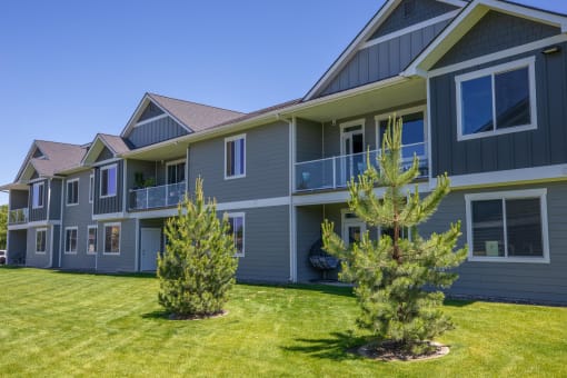 a blue house with a yard and trees in front of it at The Brix Apartments, Spokane Valley, WA, 99037